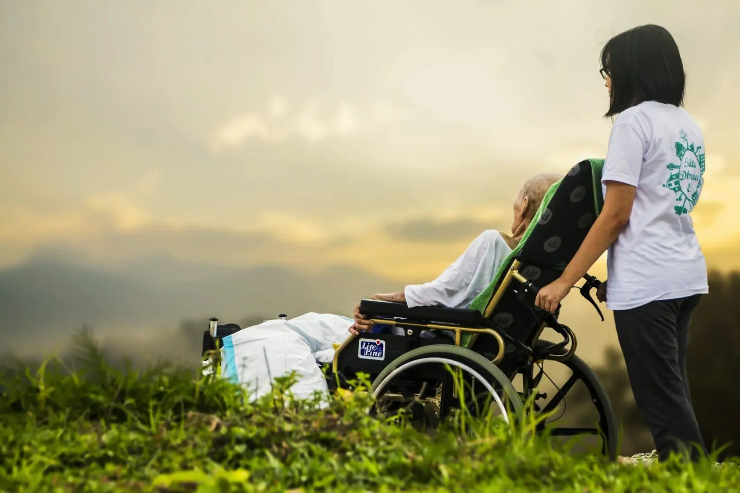 Pflegeteam mit Hand und Herz, Krankenschwester hält den Rollstuhl eines alten Mannes